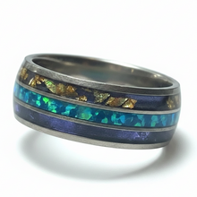 Load image into Gallery viewer, A silver-toned band ring featuring a central inlay with a blue-green opal stripe and gold-colored mineral flecks, shown on a white background.