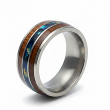 Load image into Gallery viewer, A stainless steel band ring featuring a double inlay of dark brown wood and iridescent blue-green abalone shell, shown on a white background with a soft shadow.