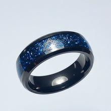 Load image into Gallery viewer, A black stainless steel ring featuring a blue glitter inlay with a silver Celtic knot design, shown on a light gray background.