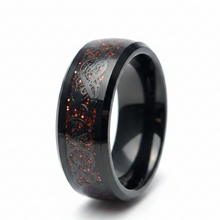 Load image into Gallery viewer, A black stainless steel band ring featuring an intricate Celtic knot pattern over a textured, red speckled inlay, shown on a clean white background.