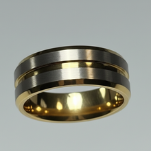 Load image into Gallery viewer, A pair of minimalist two-tone rings displayed on a white cone stand against a light gray background. The rings feature a brushed silver-toned center band with polished gold-toned outer bands.