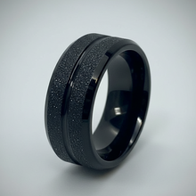 Load image into Gallery viewer, A black ring band with a textured, speckled outer surface and a smooth, polished inner channel, shown on a light gray background.