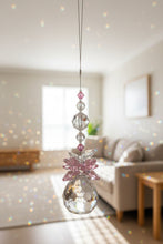 Load image into Gallery viewer, A hanging crystal suncatcher with a faceted clear ball, pink crystal detail, and small pink and clear beads on a thin wire, shown against an indoor wall.
