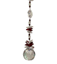 Load image into Gallery viewer, A hanging crystal suncatcher with dark red beads, clear faceted crystal discs, and a large clear crystal ball at the bottom, shown hanging against an off-white wall.
