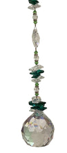Load image into Gallery viewer, A hanging crystal suncatcher with a large faceted clear glass sphere at the bottom, connected by a vertical string of green and clear beads.
