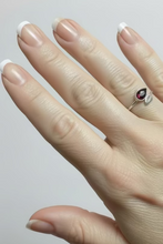 Load image into Gallery viewer, sterling silver ring with a garnet gemstone teardrop-shaped stone, with rows of other rings displayed on a tray in the blurred background.
